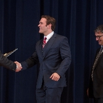 Doctor Potteiger shaking hands with an award recipient in a grey suit and red tie